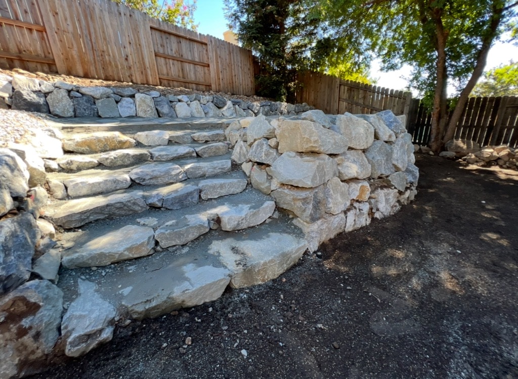 Natural stone retaining wall with flagstone steps in backyard
